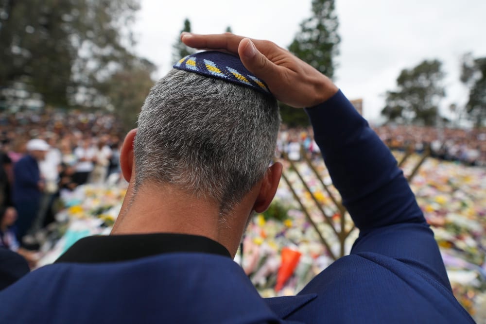 A man touches his kippah during a menorah lighting ceremony at a floral memorial for victims of the Bondi Beach shooting on Dec. 16, 2025 in Sydney, Australia.