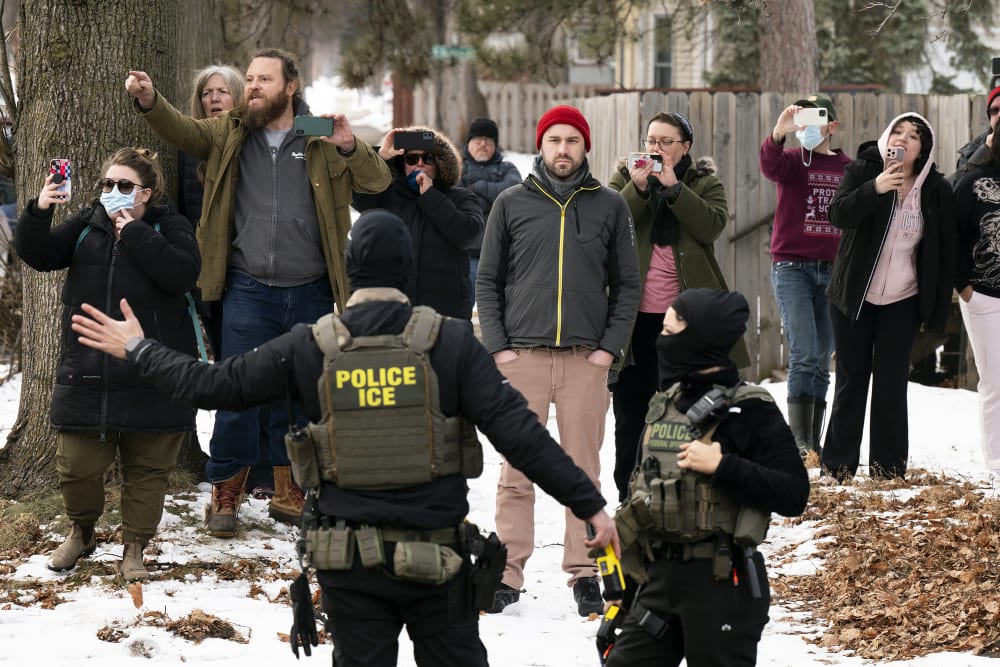 Observers film ICE agents as they hold a perimeter in Minneapolis.