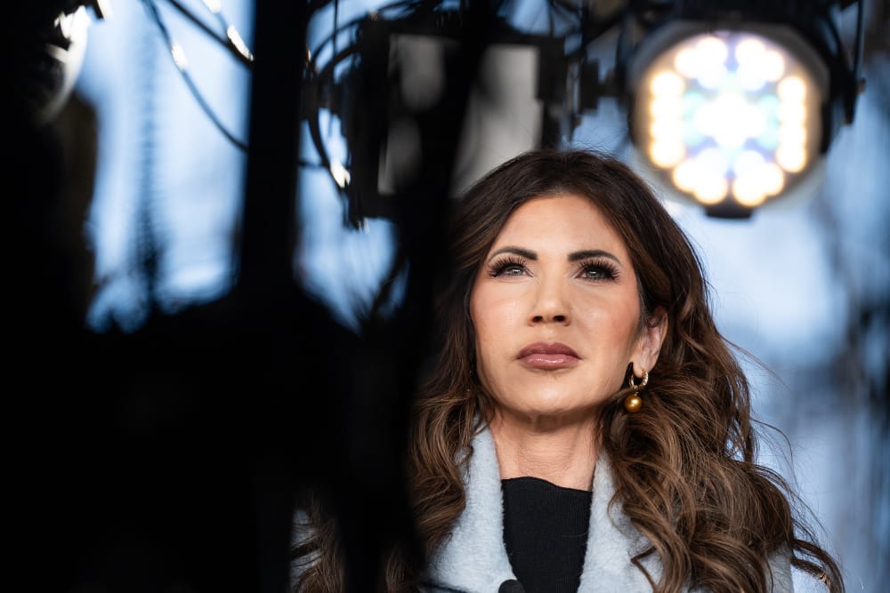 Kristi Noem can be seen through the TV cameras and lights during an interview.