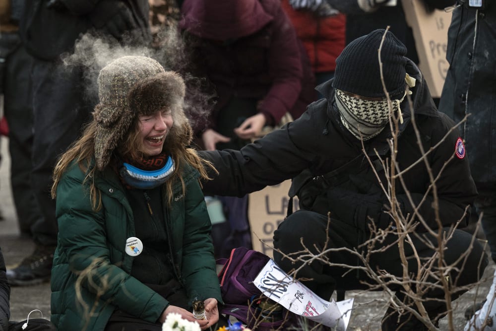 A woman cries where Alex Pretti was shot and killed by federal agents.