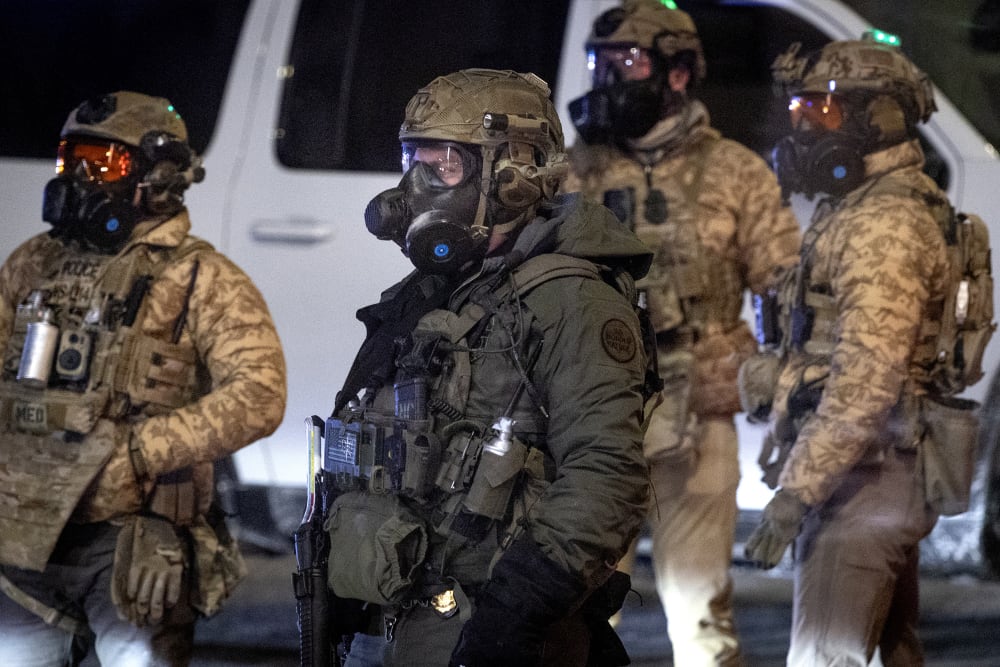 Federal agents stand outside at night.