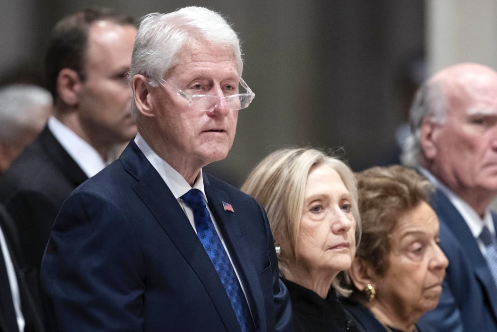 Bill and Hillary Clinton stand in the pews of the National Cathedral.