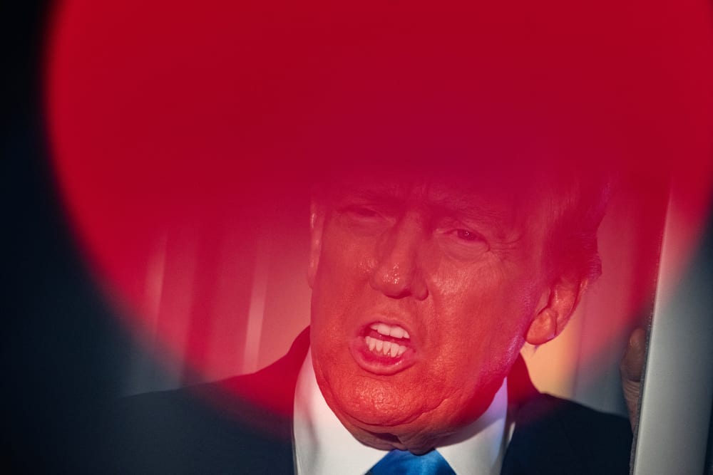 Top part of Donald Trump's face is seen through a round red light.