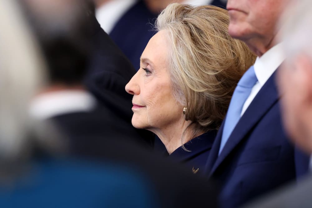 Hillary Clinton is seen from the side among a crowd of people.