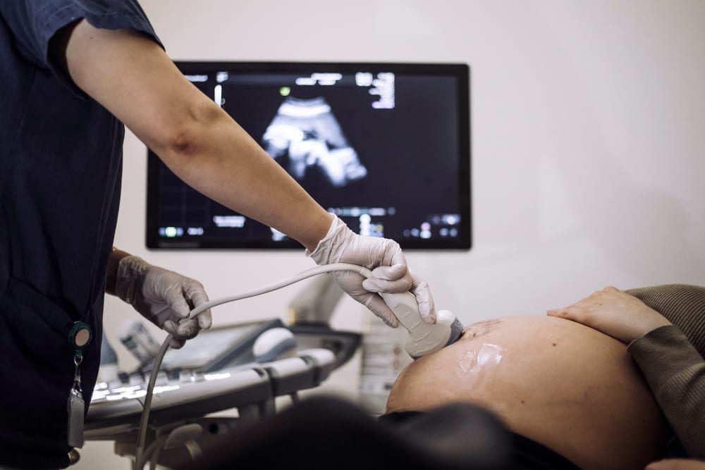 A doctor performs ultrasound on a pregnant patient.