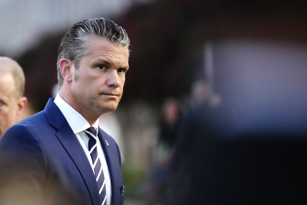Pete Hegseth looks on on the side left side of the frame, his surroundings are out of focus.