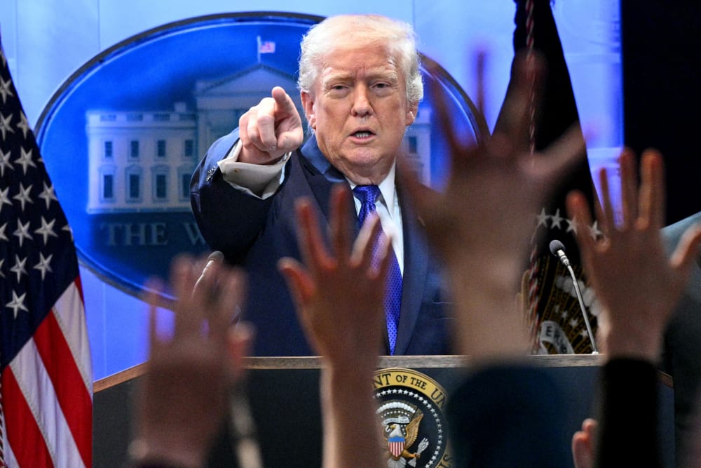 Donald Trump points at a press member as they raise their hands to ask questions.
