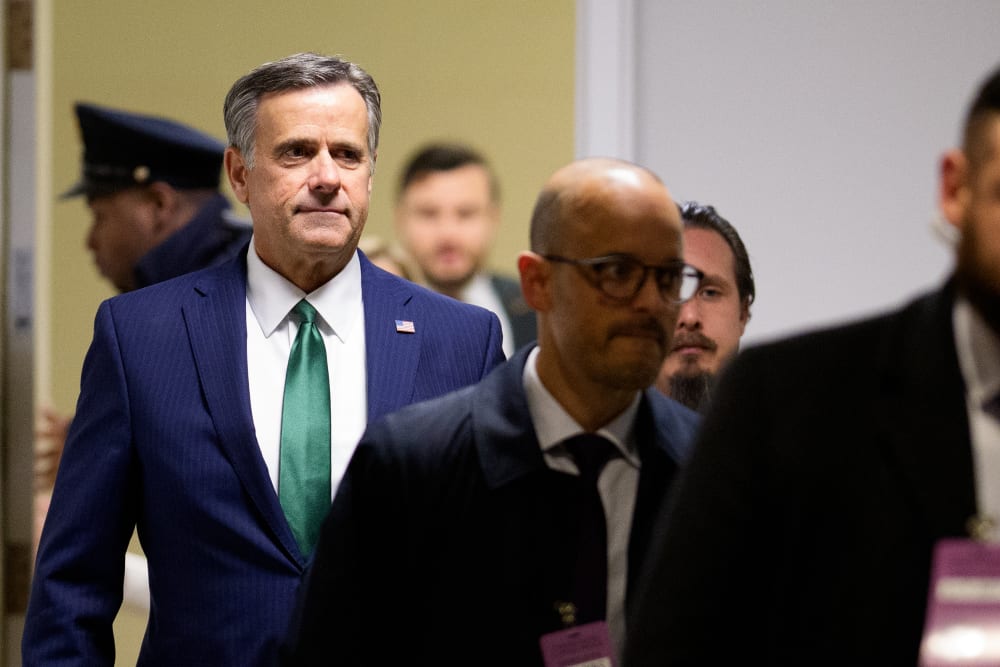 John Ratcliffe walks down a hallway behind other individuals.