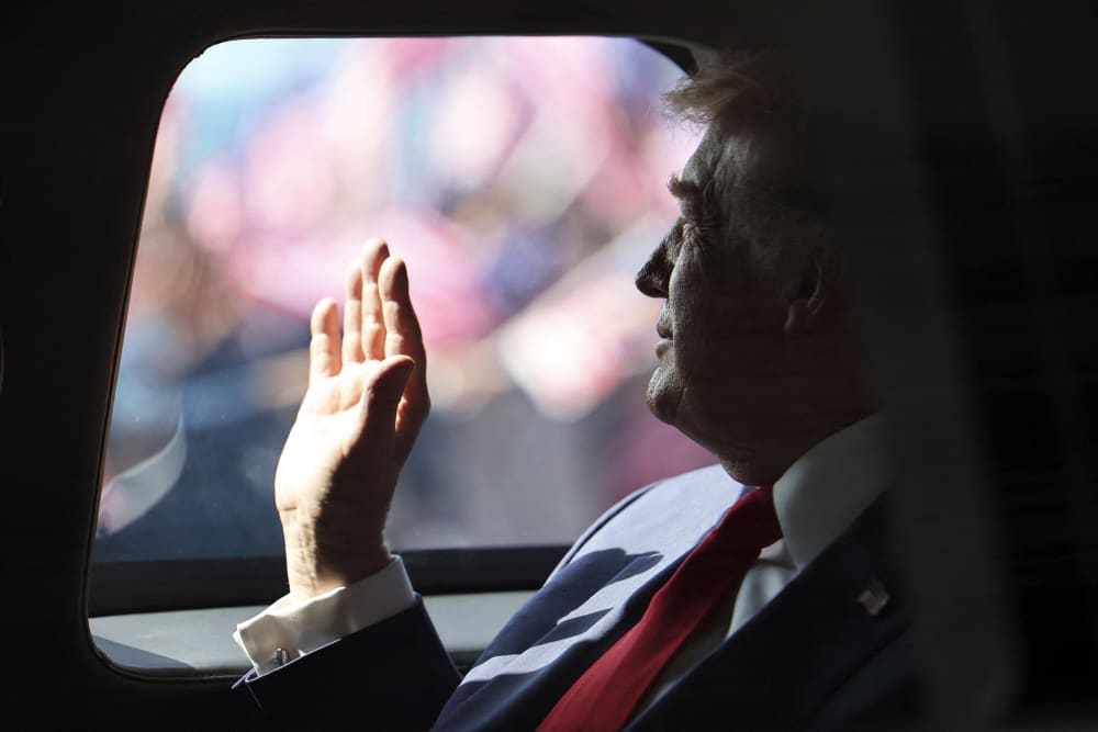 President Donald Trump waves from his official vehicle as he departs from Kuala Lumpur International Airport.