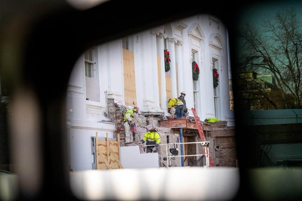 Construction workers take down material where the East Wing used to connect to the White House.
