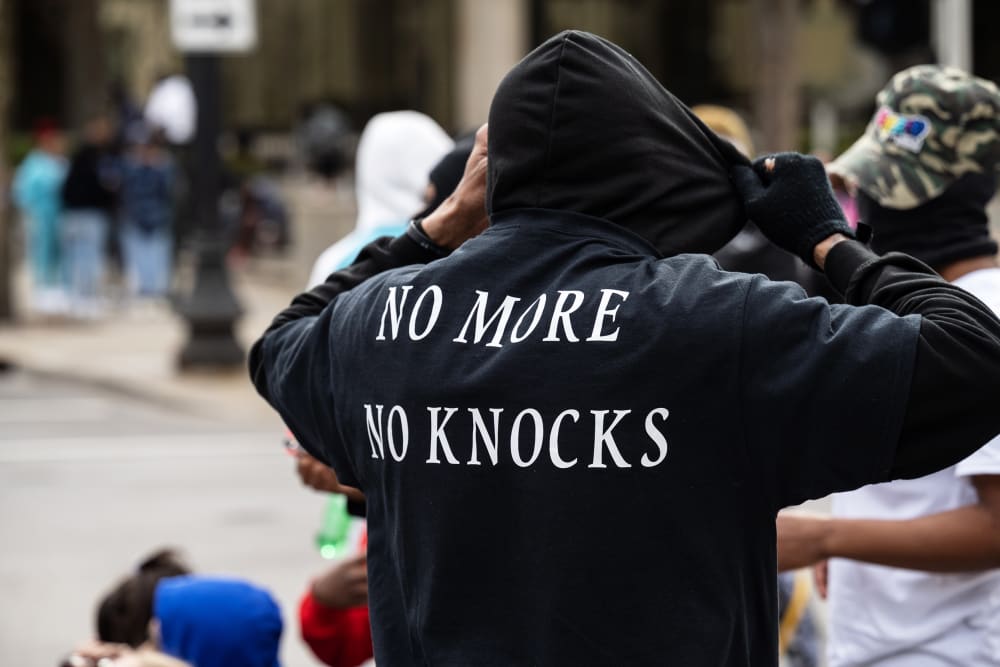 a person is seen from behind as he adjusts his black hoodie.