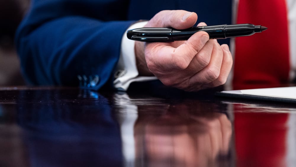 A close up of President Donald Trump's hand holding a pen.