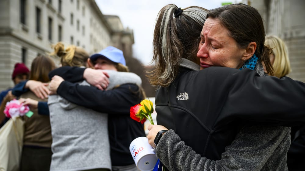 Prarie Summer, a USAID contractor for almost 10 years, right, cries as she embraces a Alexandra Jung after leaving the agency's former offices at the Ronald Reagan Building and International Trade Center.