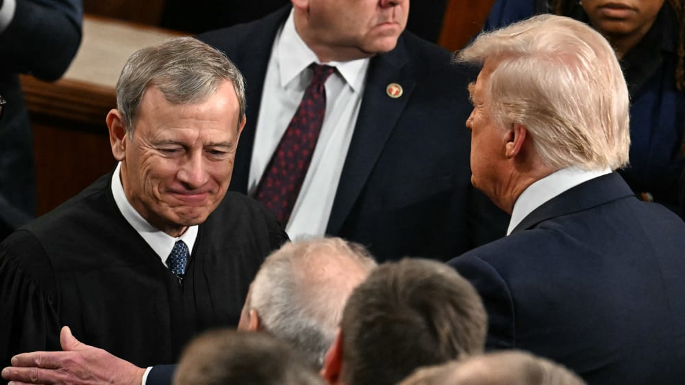 President Trump, right, pats Chief Justice Roberts arm ina crowd of people.