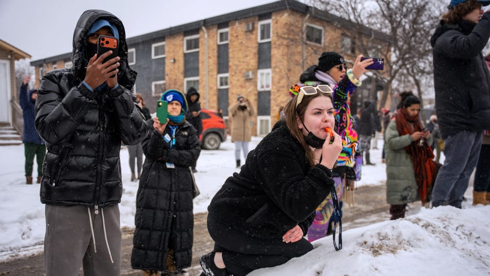 People use their phones to record and blow whistles in the snow.