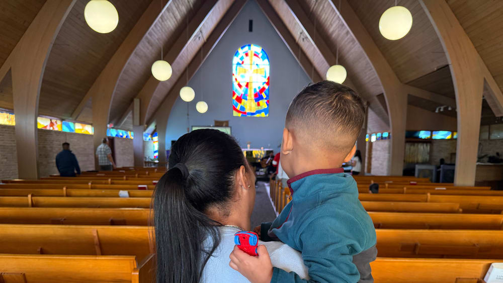 A woman holds a young child in a church