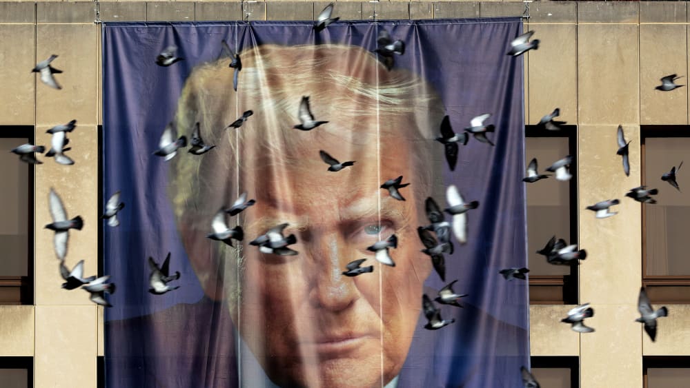 Birds fly past a giant banner with the image of President Donald Trump on Jan. 05, 2026 hanging on the outside of the U.S. Department of Labor.