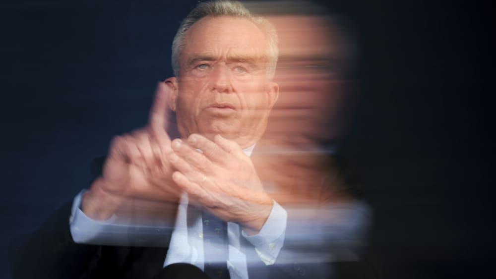 A slow shutter speed shows RFK Jr. talking on a stage.