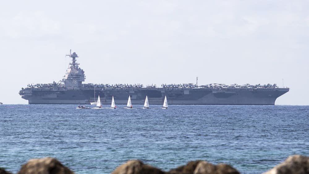USS Gerald Ford ship is seen in the distance in the ocean.