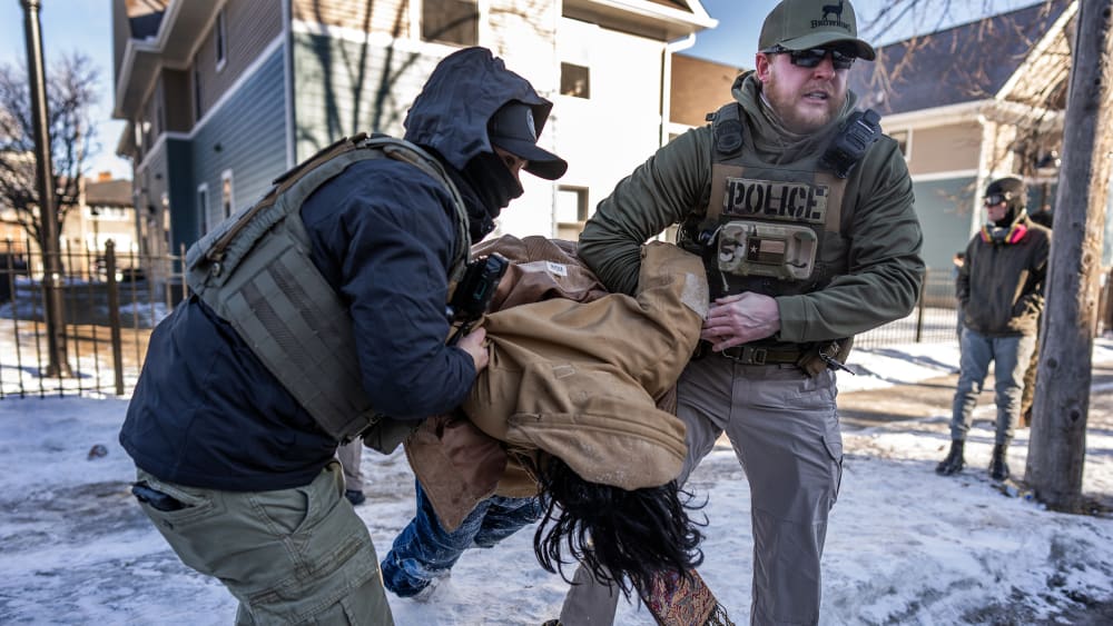 Two agents are carrying a person as they arrest them.