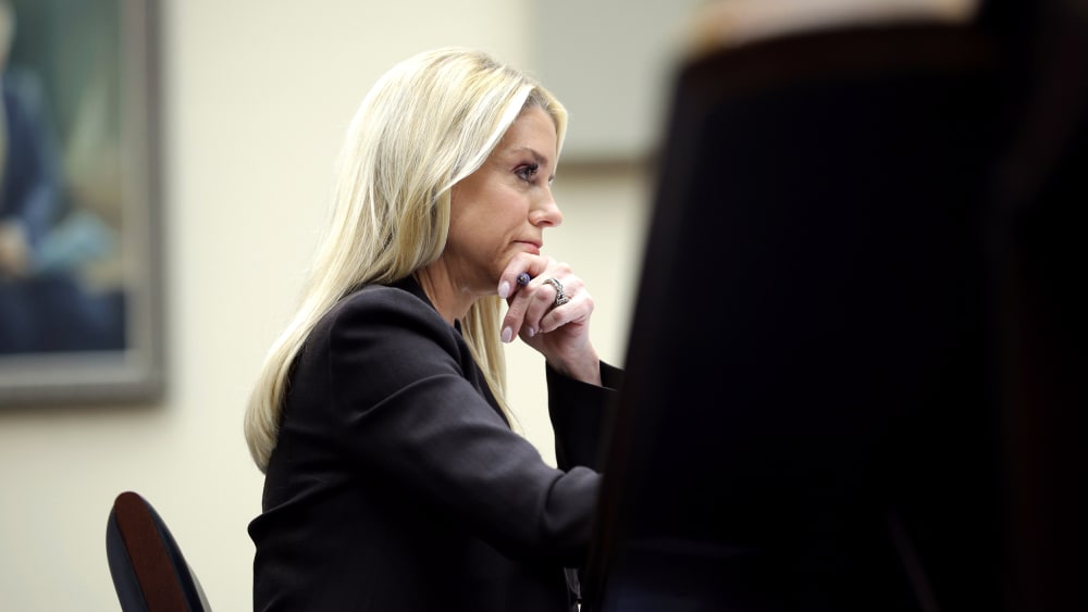 Pam Bondi, seen at profile, looking ahead with her hand on her chin.