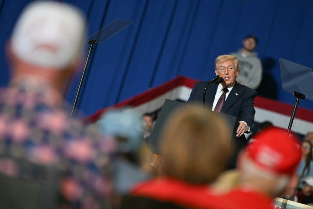 In a tilted frame, Donald Trump is seen speaking in front a small crowd in North Carolina.