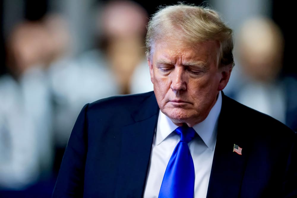 Donald Trump walks down the hallway, looking down, in a closeup photograph.