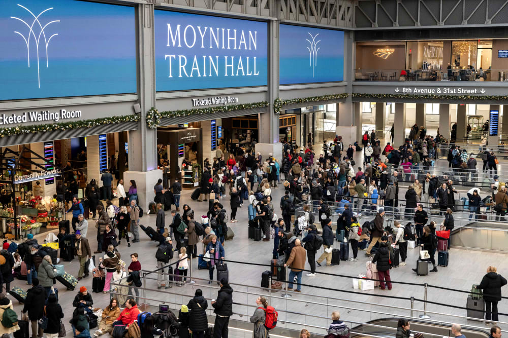 Passengers wait in the grand hall at Penn station in this wide frame shot from above.
