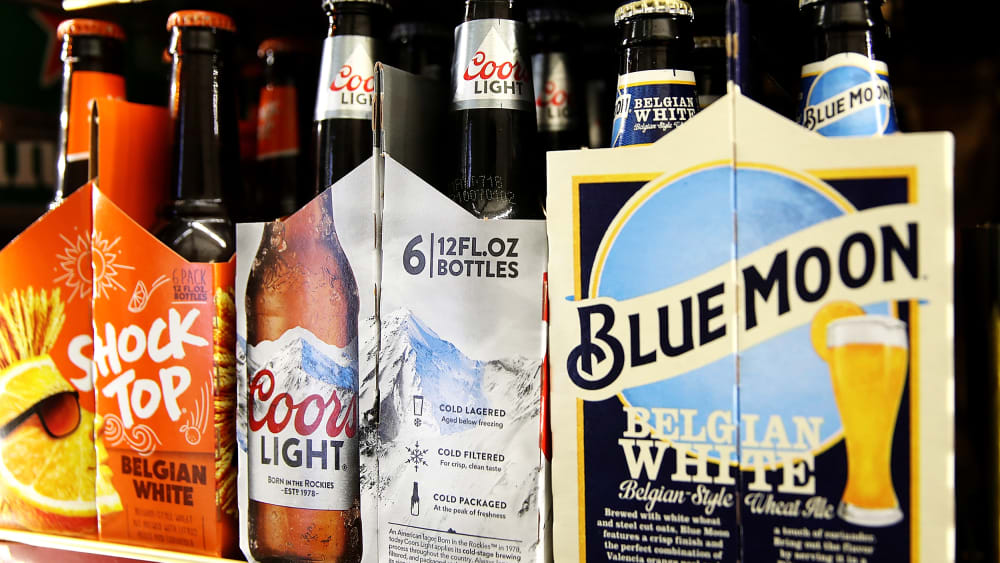 3 six-pack beers sit on a shelf.