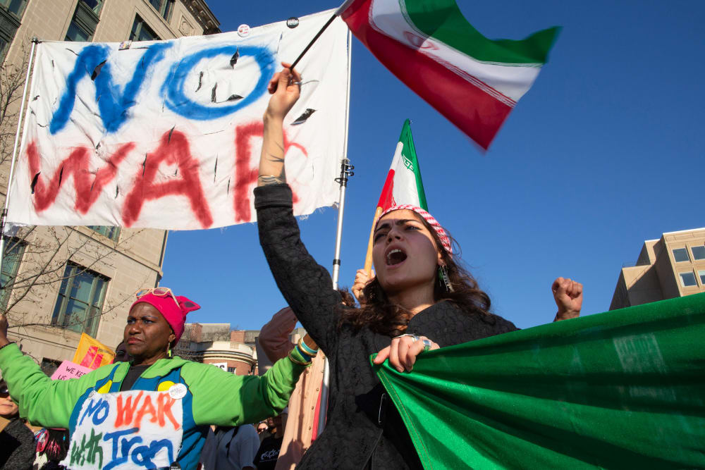 People wave Iranian flags and hold signs that say "NO WAR" and "NO WAR with Iran."