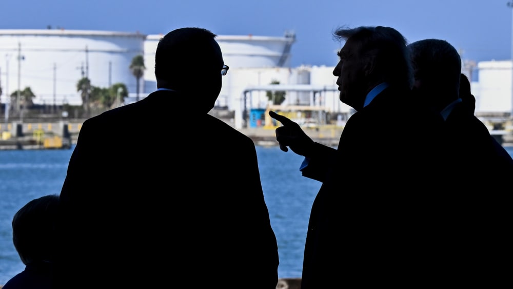 Donald Trump is seen pointing at something in this photo that shows silhouettes of his and other men.