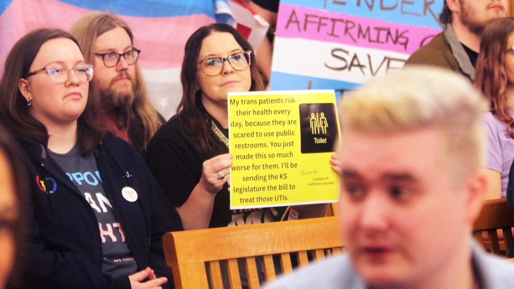 Several people hold up pro-transgender rights signs.