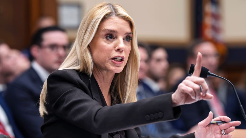 Pam Bondi raises her index finger, looking agitated, as she testifies.
