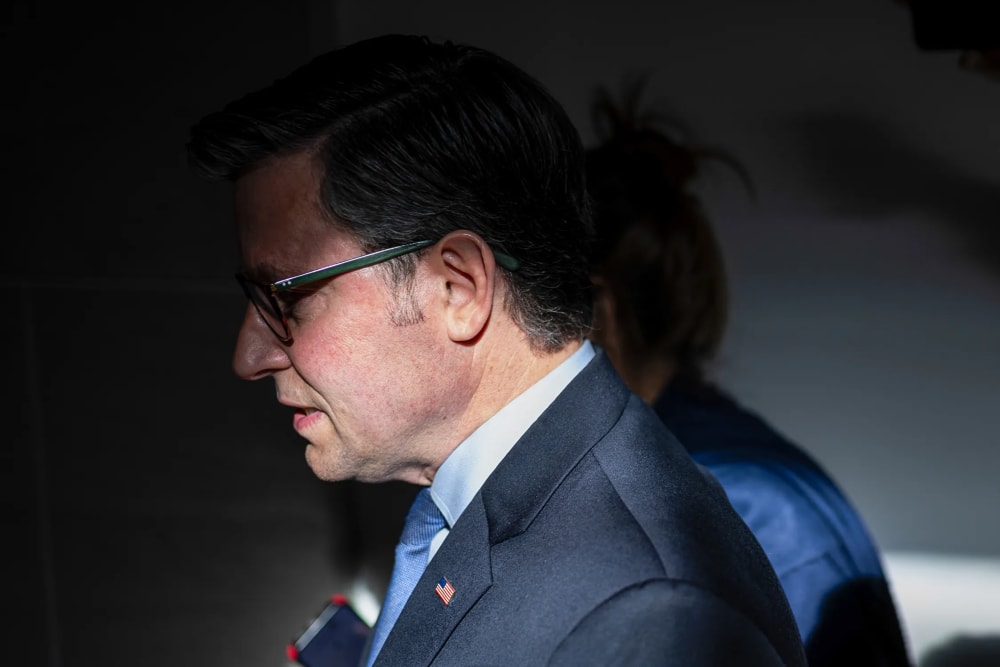 Mike Johnson seen at profile, his face partially obscured in shadow.