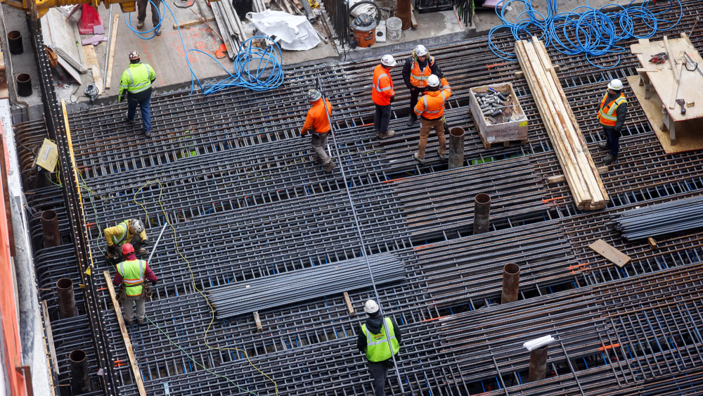 Construction workers are seen from above as they work.