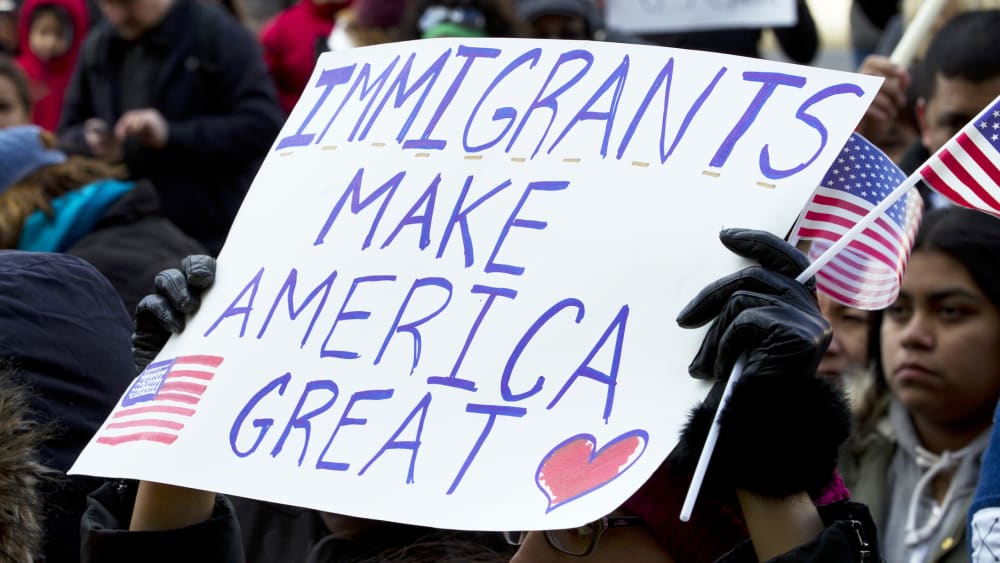 Supporters of immigrants' rights march in downtown Washington, D.C. holding sign that reads "Immigrants Makes America Great."