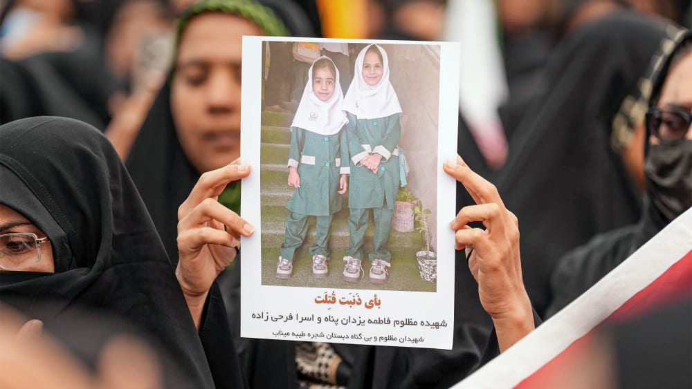 Mourners hold a portrait of a students during a funeral ceremony for children who were killed after a primary school was targeted in US and Israeli attacks in Minab, Iran.