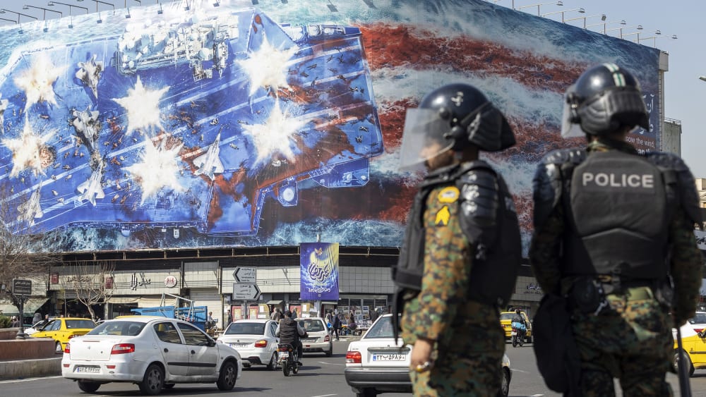 Twon officers stand in the street while a big billboard is seen in the background.
