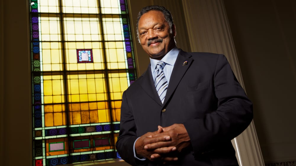 Rev. Jesse Jackson poses in front of a stained glass window.