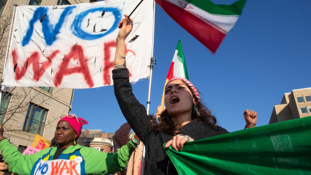 People wave Iranian flags and hold signs that say "NO WAR" and "NO WAR with Iran."