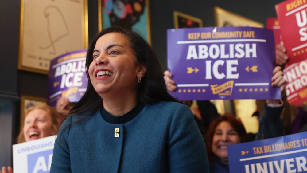 Analilia Mejia. People behind her hold signs in support.