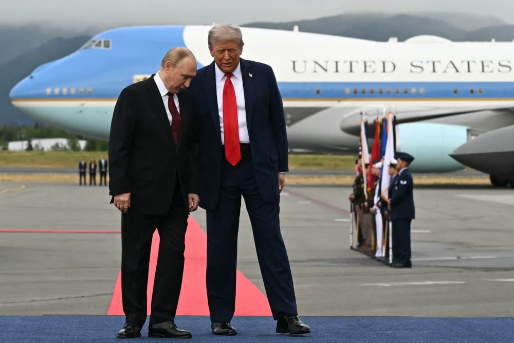 U.S. President Donald Trump, right, and Russian President Vladimir Putin pose on a podium on the tarmac after they arrived at Joint Base Elmendorf-Richardson in Anchorage.