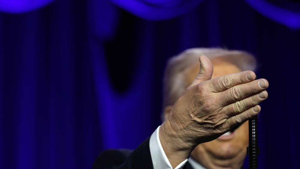 Donanld Trump's right hand obscures his face as he speaks at the National Prayer.