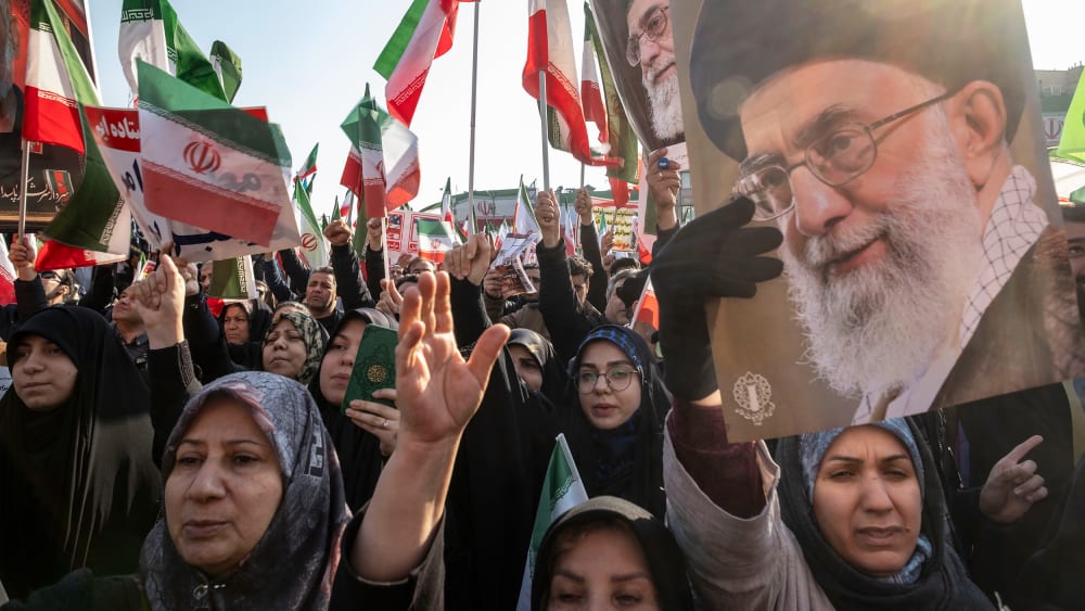 People wave Iranian flags and carry portraits of Ayatollah Ali Khamenei.