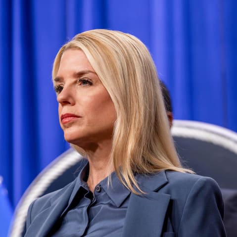 Pam Bondi, left, and Kash Patel in front of a blue curtain.