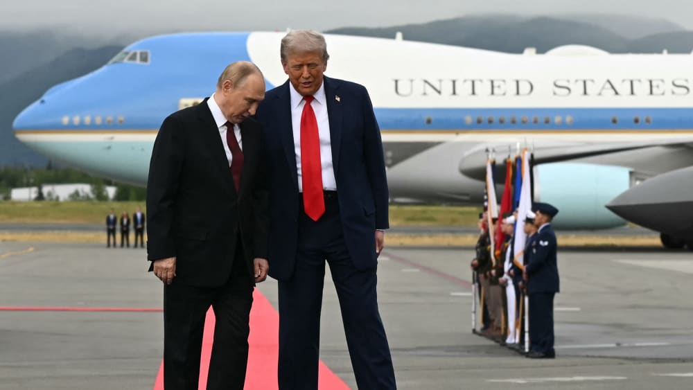 U.S. President Donald Trump, right, and Russian President Vladimir Putin pose on a podium on the tarmac after they arrived at Joint Base Elmendorf-Richardson in Anchorage.
