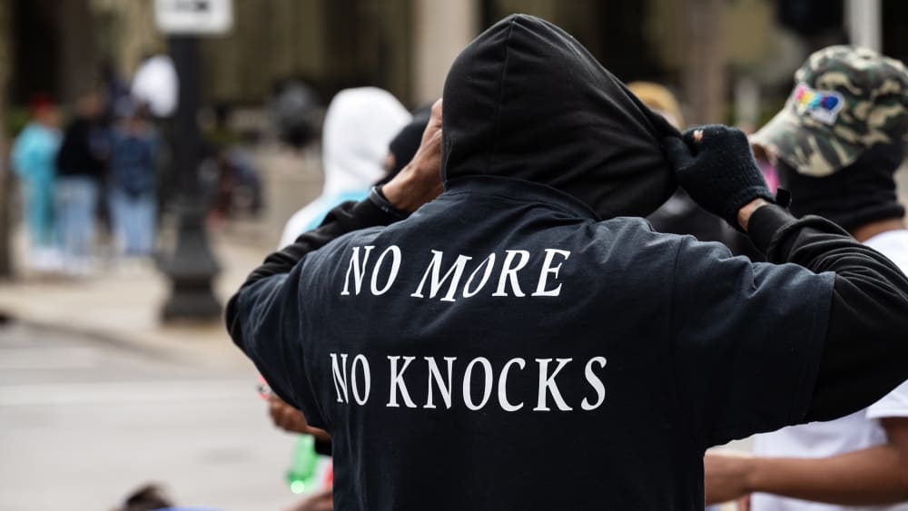 a person is seen from behind as he adjusts his black hoodie.