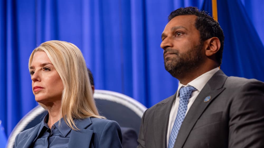 Pam Bondi, left, and Kash Patel in front of a blue curtain.