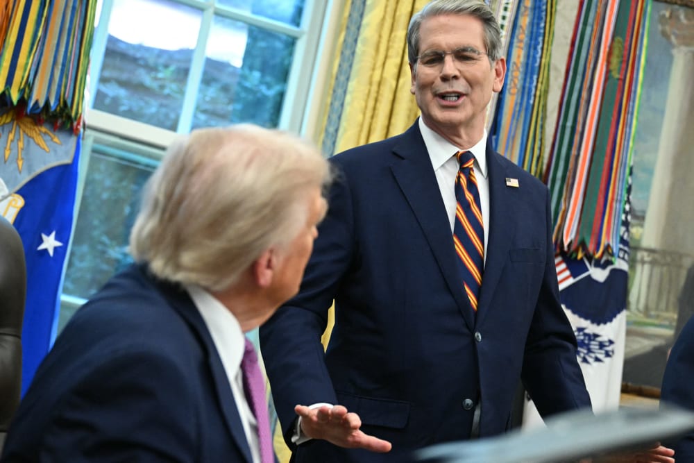 President trump, sitting-left, listens to Scott Bessent, standing-right, at the Oval Office.