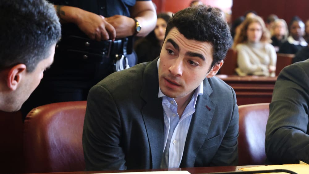 Luigi Mangione talks to a man as he sits in the court room.